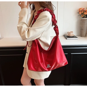 Detailed view of large red glossy PU leather shoulder bag with ruffled strap and logo