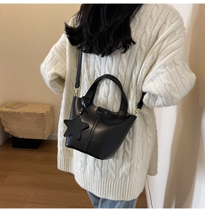 Détail du sac seau noir en cuir PU avec pendentif étoile et coutures verticales fines