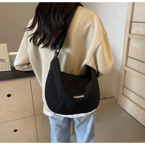 Rear view of a black nylon crossbody bag with adjustable strap on a female model