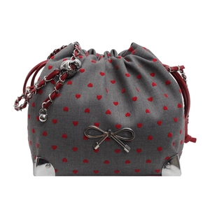 Grey fabric bucket bag with red heart patterns and silver bow decoration on white background
