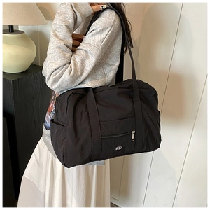 Detail shot of black nylon shoulder bag with white VELLA logo and zip pocket
