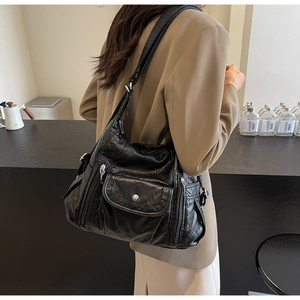 Detail of a black PU leather shoulder bag with multiple silver zipper pockets and crinkled texture