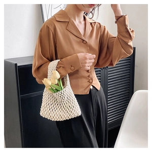 Close-up of caramel satin blouse texture with a handmade woven hollow handbag detail