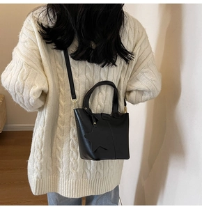 Détail du sac seau noir en similicuir avec breloque étoile et finitions dorées