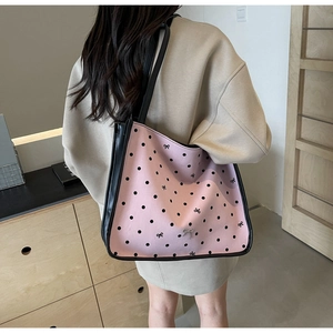 Detail of a large pink polka dot tote bag with bow embroidery and black leather trim