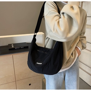 Detail of black nylon crossbody bag with fashion label and adjustable strap