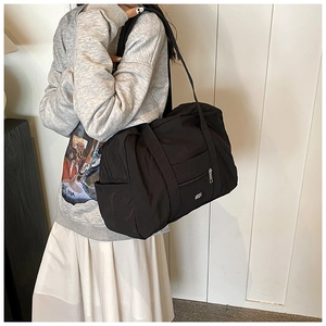 Detail showing spacious black nylon shoulder bag with side pockets and durable strap