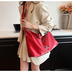 Detail of red patent leather tote bag with metallic logo on a professional beige suit