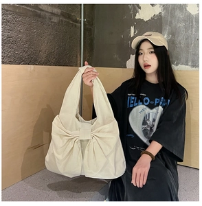 Détail d'un sac cabas en toile beige avec un grand nœud 3D et une bandoulière élégante