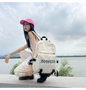 Outdoor lifestyle shot of a cream nylon backpack with black straps and side buckles