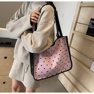 Detail of pink polka dot tote bag with black leather trim and bow metal charm