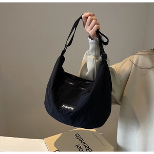 Detail of black nylon crescent crossbody bag with Fashion label and adjustable strap