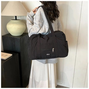 Black nylon shoulder bag featuring large capacity and VELLA logo in a minimalist setting