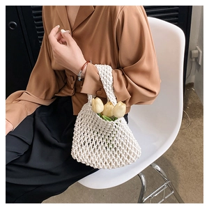 Detail of white crochet woven handbag with intricate mesh pattern and floral accents