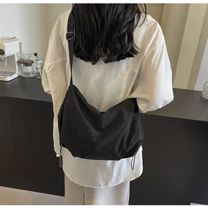 Detail of minimalist black nylon crossbody bag with adjustable wide strap on model