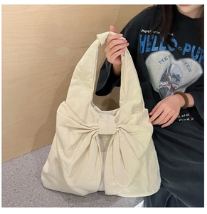 Vue détaillée du grand sac cabas en toile crème avec un design décoratif à gros nœud