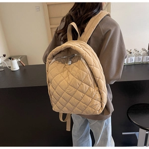 Detail eines khakifarbenen Stepprucksacks mit Rautenmuster und Doppelreißverschluss am Model