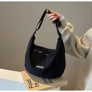 Detail view of black fabric crescent bag with adjustable wide strap and fashion label