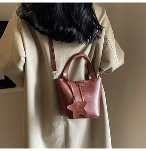 Sac seau en cuir PU marron avec breloque étoile et bandoulière porté par un mannequin