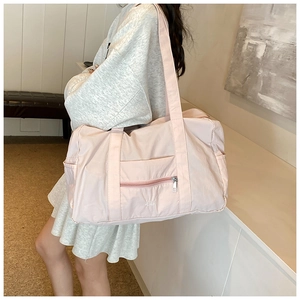 Detail of light pink waterproof nylon travel bag showing large capacity and zipper pocket