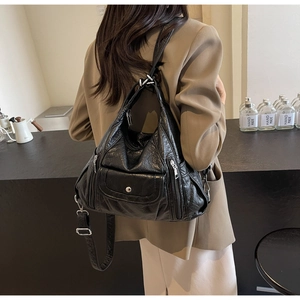 Close-up of black PU leather backpack with silver zippers on a model in a cafe