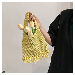 Detail of yellow hollow knit cotton rope tote bag with tassels for beach or casual use
