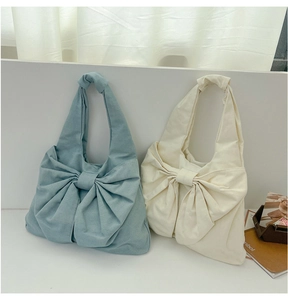 Vue détaillée de sacs cabas en toile avec de grands nœuds décoratifs bleu clair et beige