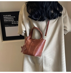 Détail d'un sac seau vintage en PU marron avec bandoulière réglable et breloque étoile