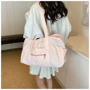 Model wearing a large light pink nylon travel bag with UDIA embroidery and zip pocket