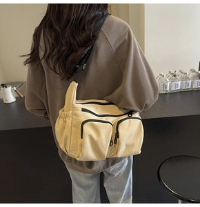 Detail of beige canvas crossbody bag with multi-zipper pockets and wide strap