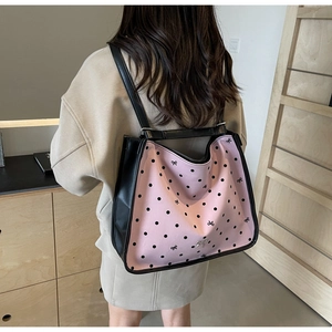 Close-up of pink polka dot tote bag with black bow details and silver heart pendant