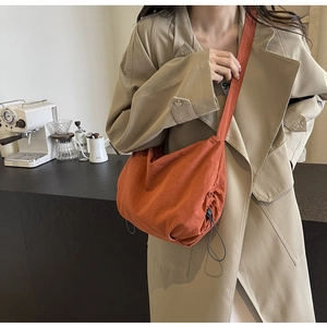 Burnt orange nylon crossbody bag with drawstring closure and comfortable wide shoulder strap