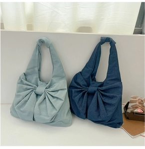 Détail de sacs cabas en denim bleu clair et foncé avec de grands nœuds décoratifs