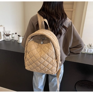 Detail eines khaki gesteppten Rucksacks mit Rautenmuster und silbernem Metallreißverschluss
