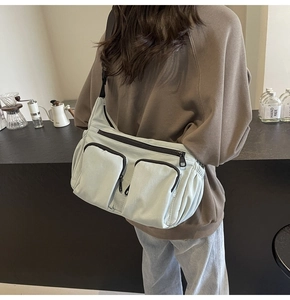 Detail of light green nylon crossbody bag with multi-pocket design on a female model