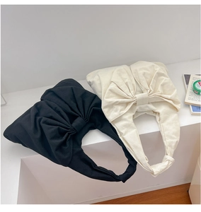Détail du design de nœud surdimensionné sur sacs fourre-tout en denim noir et crème