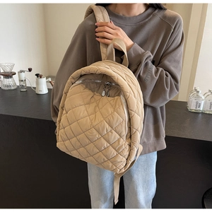 Detailansicht eines beigen gesteppten Puffer-Rucksacks mit Metallreißverschluss in Alltagsszene