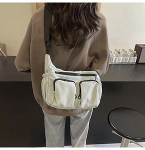 Detail view of a light green nylon crossbody bag with multi-pocket design on female model