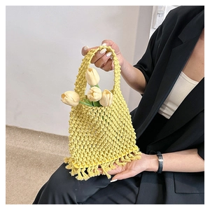 Detail of woven yellow handbag with hollow diamond texture and long fringe tassels