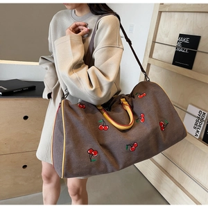 Detail of vintage canvas travel bag with cherry print and adjustable shoulder strap