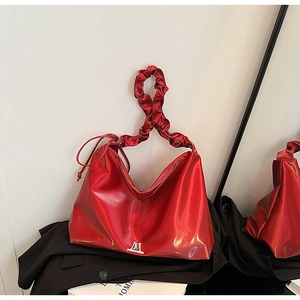 Metallic red PU leather shoulder bag with ruched handle and sleek logo on black suit background