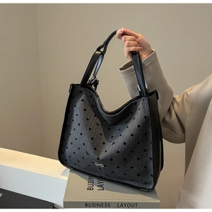 Close-up of gray polka dot tote bag with black leather trim and metal bow buckle detail
