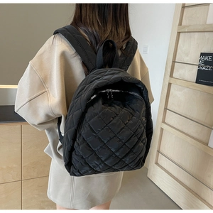 Nahaufnahme des schwarzen gesteppten Nylonrucksacks mit gepolsterten Trägern am Modell