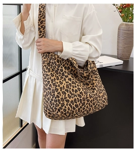Detail of large leopard print canvas tote bag with wide shoulder strap shown in a room
