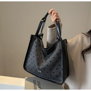Close-up of grey tweed tote bag with black polka dots and silver metal bow detail