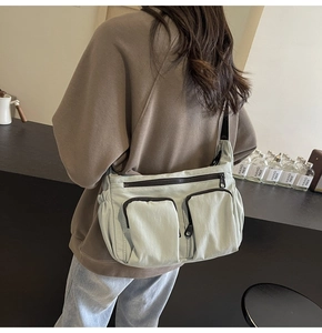 Detail view of a large capacity crossbody bag in mint green with multiple zippers
