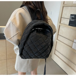 Detailaufnahme von schwarzem gestepptem Nylon-Rucksack mit Rautenmuster und Silber-Reißverschluss