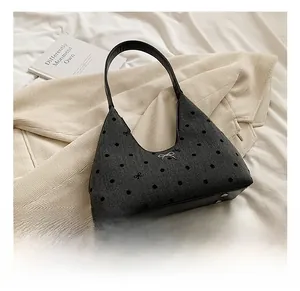 Dettaglio borsa hobo grigia a pois neri con borchie protettive sulla base in pelle nera