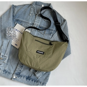 Olive green crescent nylon crossbody bag on denim jacket with adjustable strap