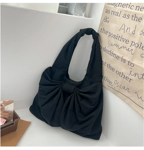 Détail d'un sac cabas en tissu noir avec un grand nœud décoratif et une anse nouée
